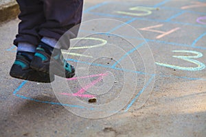 Hopscotch in a schoolyard on an asphalt floor with chalk drawings of numbers and squares as an icon of youth innocence