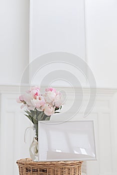 Horisontal frame mockup. Glass vase with a bouquet of pink peonies. Modern fireplace in a Scandinavian interior.