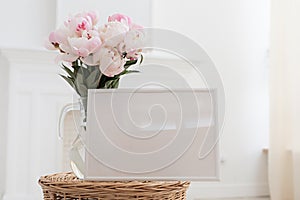 Horisontal frame mockup. Glass vase with a bouquet of pink peonies. Modern fireplace in a Scandinavian interior.