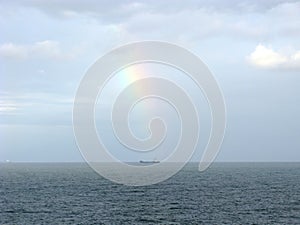 Horizon with distant ship and rainbow