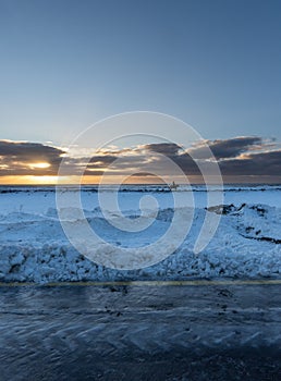 From the horizon Woman on a horse galloping along the shore of the fully snow covered black sand beach of Iceland