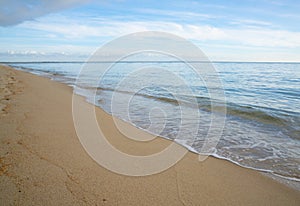 Horizontal background of gentle waves on a golden sandy tropical beach photo