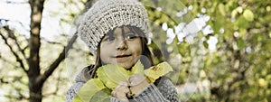 Horizontal banner or header with cute little girl holding yellow maple leaves in her hands during foliage time in the natural park