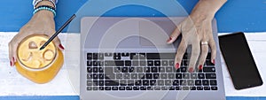 Horizontal banner or header with lady hands typing on laptop during remote working outdoors - Modern laptop on the blue wooden