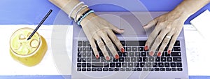 Horizontal banner or header with lady hands typing on laptop during remote working outdoors - Modern laptop on the blue wooden