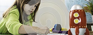 Horizontal banner or header with little girl having fun drawing with wax colors on school notebook for homework - On the desk