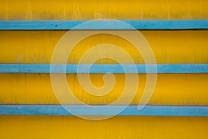 Horizontal blue lines on a dirty yellow background with shadows. rough surface texture