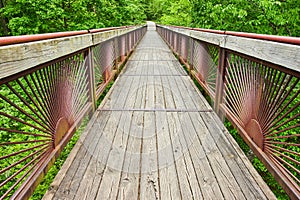 Horizontal of boardwalk bridge leading into lush green forest with trail at Bernheim Forest park