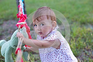 Horizontal close-up outdoor portrait of a funny little baby in a summer dress