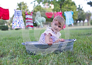 Horizontal closeup photo of funny little baby in a summer dress on a background of nature