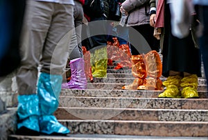 Horizontal closeup photo of a group of tourists standing in shoe covers on a stone staircase