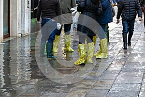 Horizontal closeup photo of tourists feet in high shoe covers protecting their feet from rain