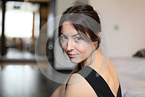 Horizontal closeup portrait of a beautiful brunette in a cocktail dress on a blurred background of home interior