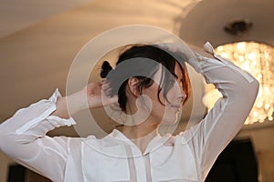 Horizontal closeup portrait of a beautiful brunette in a white blouse on a background of home interior