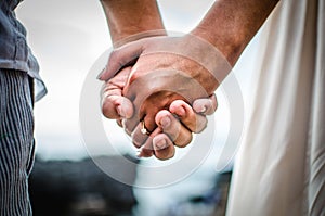 Horizontal closeup shot of a romantic couple holding hands on a background of a beautiful beach