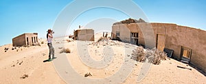 Horizontal crop of adventurous traveler photographer at Kolmanskopp ghost village near Luderitz in Namibia - Wanderlust and travel