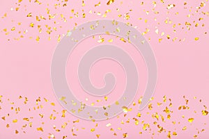 Horizontal frame of golden glitter confetti sparkles on pastel pink background. Holiday, festive, party backdrop. Flat