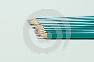 Horizontal graphite pencils on a light blue background. Selective focus.