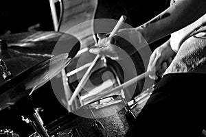 Horizontal greyscale shot of a drummer performing on the stage during a concert