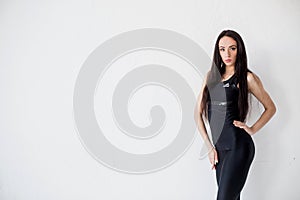 Horizontal half-length portrait of the attractive brunette with natural make-up in black sportsuit looking in camera at