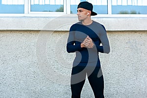 Horizontal image of a an athlete male standing on the city street in the morning. Handsome sportsman taking a break on the street