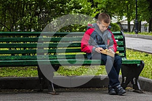 Horizontal image of boy reading a book on bench