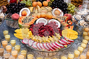 Horizontal image of festive table with cold exotic alcoholic beverages, cocktails, berries, grape, pitahaya, carambola, coconut