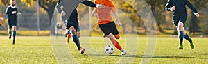 Horizontal image of football players running in a duel on a tournament match. Soccer forward player compete with defender