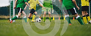 Horizontal image of kids playing football. Happy boys kicking classic soccer ball on grass field