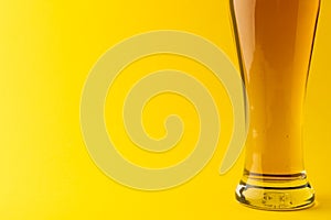 Horizontal image of pint glass of lager beer on yellow background, with copy space