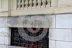 Horizontal image of stone building with carved railing and wrought iron enclosures