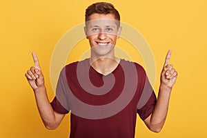 Horizontal indoor picture of emotional energetic young boy with fair hair, making gesture, raising hands, showing direction with