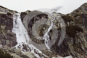 Horizontálna krajinná fotografia dvoch hmlových vodopádov vo Vysokých Tatrách na Slovensku. Skalnaté hory prírodná scenéria náladový pohľad