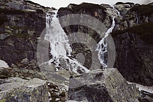 Horizontal landscape photography of two foggy waterfalls and large stone in the foreground in High Tatras, Slovakia. Rocky