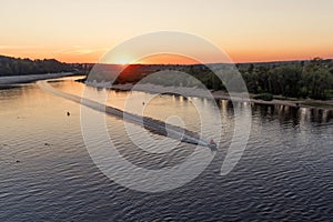 Horizontal landscape of watery surface with a hydrocycle in the rays of the orange sunset