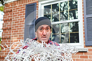 Horizontal of a man with tangled Christmas lights