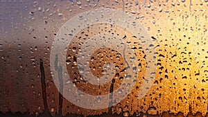 Horizontal natural background with water drops on the window with sunbeams, condensation on the glass with dripping drops