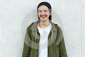 Horizontal outdoor portrait of cheerful attractive youngster, smiling, being in good mood, standing straight isolated over white