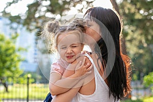 Horizontal photo from the back of a long-haired young woman with a three-year-old daughter in her arms