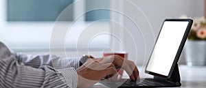 Businessman hands typing on keyboard of tablet computer at his workspace.