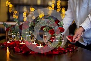 Horizontal photo close-up of the process of decorating the festive table with roses and candles