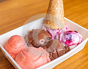 horizontal photo of delicious and creamy chocolate ice cream, strawberry and blackberry with a cono photo