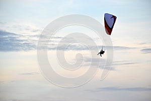 Horizontal photo of the flight of two people on a paraglider in a clear slightly cloudy sky in the summer