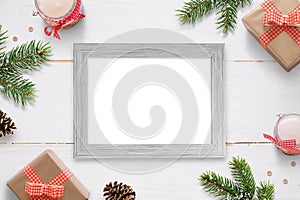 Horizontal photo frame surrounded with Christmas New Year gifts, tree branches and decorations.