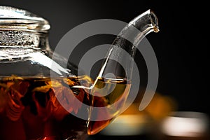 Horizontal photo of the tea set on a black background. Glass transparent teapot and cup. Black leaf tea.