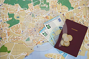 Undefined red passport with banknotes and euro coins money on top of a local map. Concept for travel budget planning.