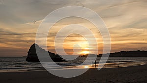 Couple walking in desert beach at sunset, with seagulls flying in sky