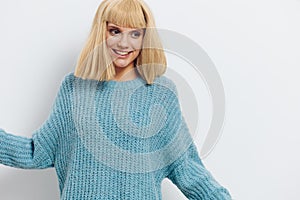 Horizontal photo, a woman on a white background in a blue sweater with beautiful blond hair joyfully looks down with her
