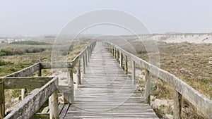 Wooden footbridge of Costa Nova beach in a foggy morning. Aveiro, Portugal