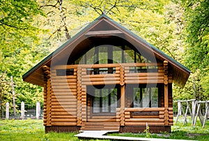 Horizontal photo of  wooden house in  green forest. Pros and cons of  wooden house and suburban real estate concept